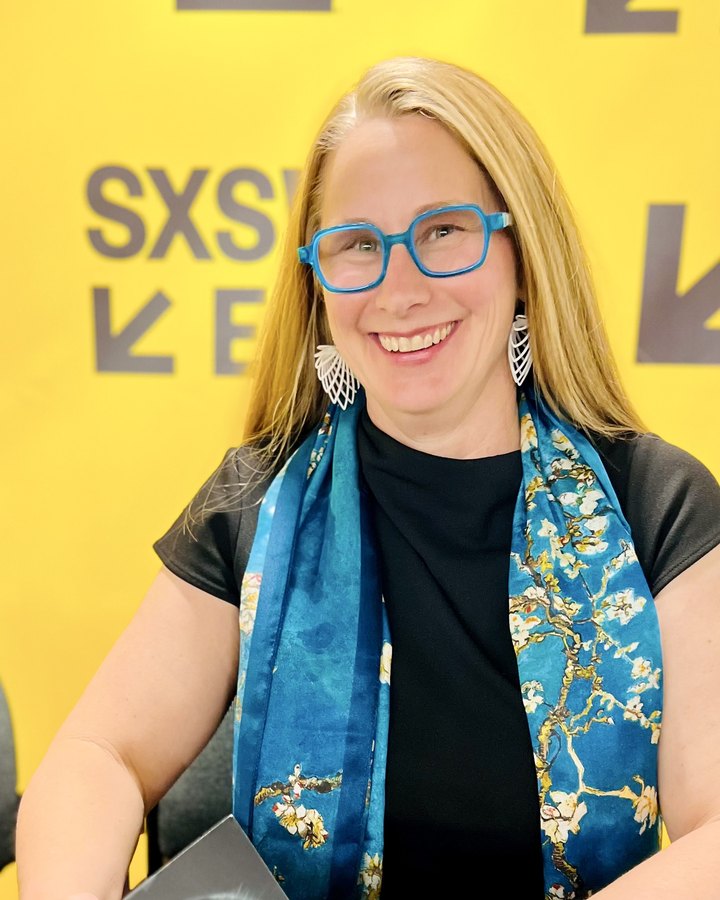Beth Rudden at SXSW EDU in blue glasses and her Van Gogh almond-blossom scarf, beside a copy of AI for the Rest of Us.